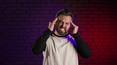 Stüdyoda baş ağrısı çeken sakallı adam.