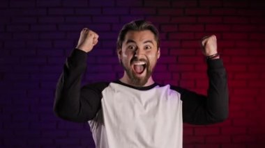 Stüdyoda mutluluktan el kol hareketi yapan heyecanlı beyaz adam.