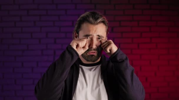 Απογοητευμένος άντρας να σκουπίζει δάκρυα ενώ κλαίει στο στούντιο — Αρχείο Βίντεο