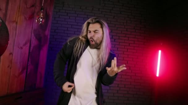Young man with long hair playing air guitar in studio — Video