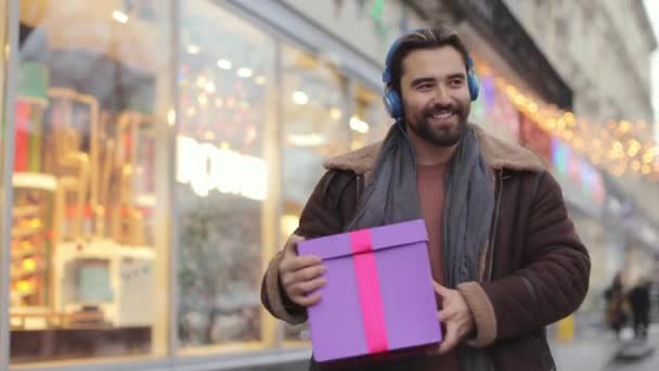 Man in headphones walking and dancing with gifts in hands — Stock videók