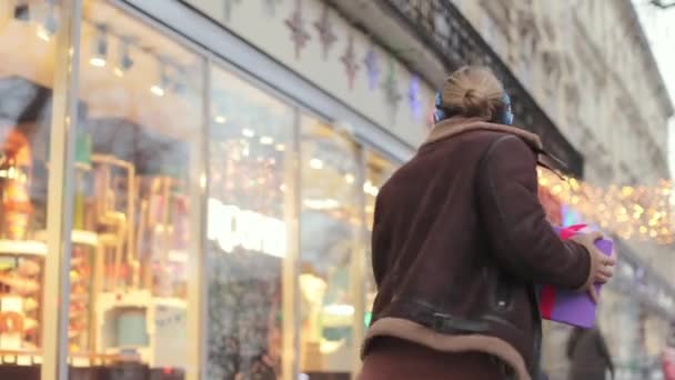 Homem em fones de ouvido dançando engraçado com presente de Natal na rua — Vídeo de Stock