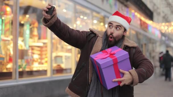 Man with gift box taking selfie on smartphone outdoors — Stock videók
