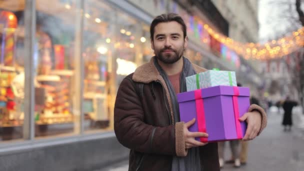 Mannen med julklappar står nära fönsterbutiken — Stockvideo