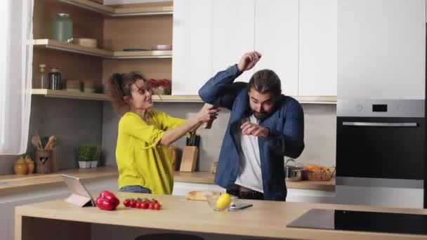 Positive woman hitting her husband with baguette on kitchen — Stock Video
