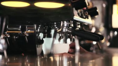 Modern kahve makinesinden beyaz seramik bardakta taze demlenmiş kahve dökülüyor. Lüks restoranda misafirler için sıcak aroma içeceği hazırlayan barmeni kapatın..