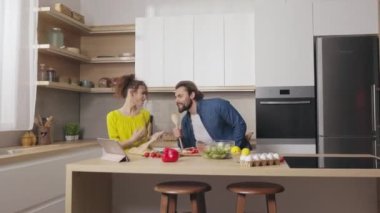 Neşeli çift, ev mutfağında birlikte yemek hazırlarken dans ederek ve şarkı söyleyerek eğleniyor. Kafkasyalı erkek ve kadın boş zamanlarını kullanışlı ve mutlu geçiriyorlar..