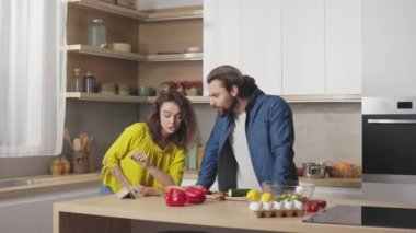 Parlak mutfakta yemek pişirirken dijital tablette yemek tarifi arayan sevimli genç çift. Güzel bir kadın ve yakışıklı bir erkek evde boş vakit geçiriyorlar..