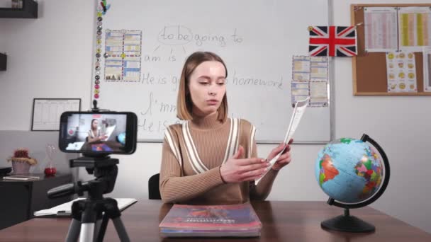 Uśmiechnięty Nauczyciel Pokazuje Listę Zadań Domowych Macha Pożegnanie Zdalnie Uczniom — Wideo stockowe