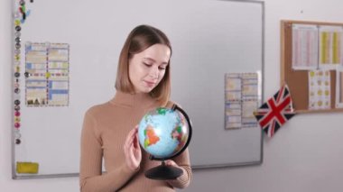 Modern sınıfta küçük bir dünyayı tutan ve döndüren genç bayan öğretmenin portresi. Yabancı dil, dünya çapında ve insanların kavramı.