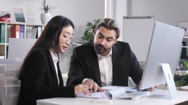 Sakallı işadamı ve iş kadını iş yerindeki belgeleri kontrol edip karşılaştırıyor. Mutlu kadın ve erkek çalışanlar başarılı takım çalışmalarından sonra el sıkışıyor..