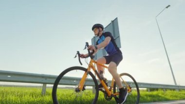 Dışarıda yoğun kardiyo antrenmanı sırasında siyah kasklı ve bisiklet süren bir adam. Uluslararası triatlon yarışması için formda sporcu eğitimi.