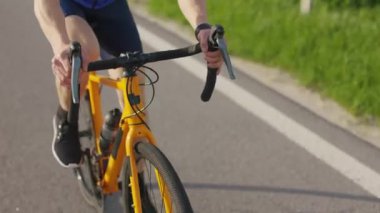 Bisikletli ellerin bisiklet yarışında gidona tutunması ve asfalt yolda hızlı sürmesi. Triatlon yarışması için güçlü sporcu eğitimi.