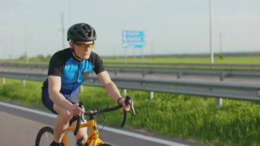 Spor ekipmanları, ayakkabılar, kasklar ve güneş gözlükleriyle asfaltlanmış otoyolda giden profesyonel bisikletçilerin ön görüntüsü. Uluslararası triatlon yarışmasına ciddi bir adam eğitimi.