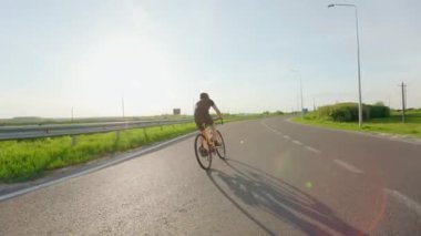 Temiz havada profesyonel triatlon bisikletinde kask eğitimi alan formda bir bisikletçi. Genç beyaz adam yaz aylarında yolda pedal çeviriyor..