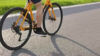 Güçlü bisikletçi bacakları pedal çeviriyor, tekerlekleri hızlı dönüyor. Uluslararası yarış için bilinmeyen adam eğitimi. Bacak kaslarını kapat..