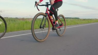 Bir çift bisikletçi güzel yeşil doğada yolda gidiyor. Profesyonel yol bisikleti kullanan erkekler dışarıda bisiklet eğitimi alıyor. Spor ve triatlon konsepti.