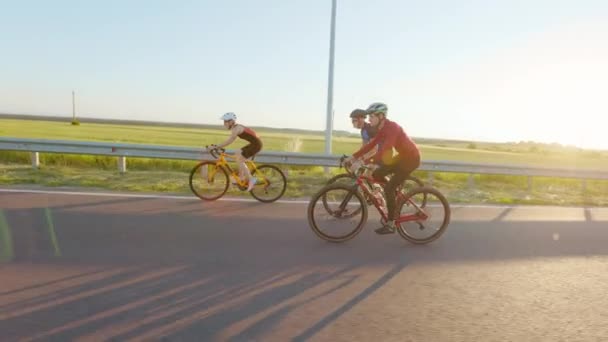 緑の夏のフィールドを背景に道路上でサイクリングを練習白人男性と女性の友人の側のビュー レース 定期的なトレーニングの概念 — ストック動画