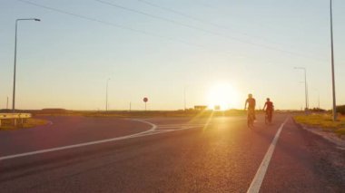 Spor kasklı ve kasklı atletik erkekler ve kadınlar temiz havada bisiklet sürmek için bisiklet kullanıyorlar. Arka planda güzel bir yaz günbatımı. Etkin hobi.