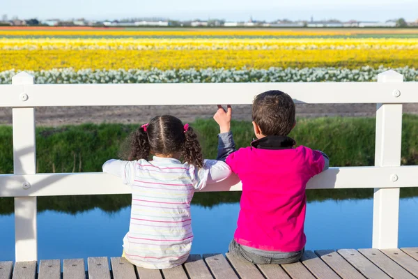 Ragazza e ragazzo guardando attraverso recinzione al campo di fiori — Foto Stock