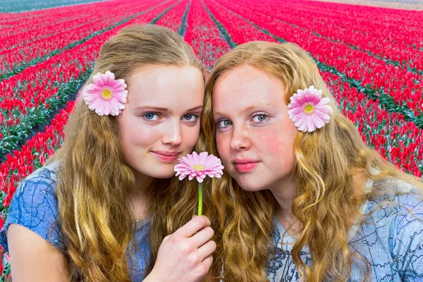 Dos adolescentes frente al campo de tulipanes rojos —  Fotos de Stock