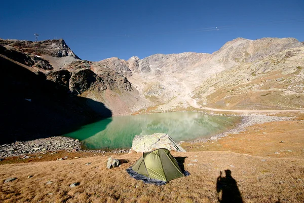 Tienda en el vivac en un lugar de descanso junto al lago en el prado de los Alpes suizos —  Fotos de Stock