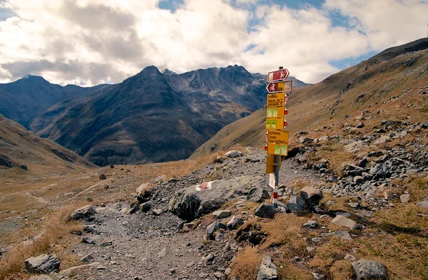 Panneau de randonnée sur prairie alpine d'herbe entourée de hautes montagnes dans les Alpes suisses — Photo