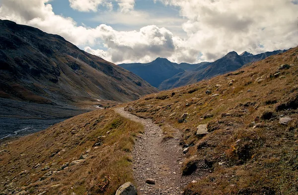 Sendero rocoso que conduce al valle rodeado de altas montañas en los Alpes suizos — Foto de Stock