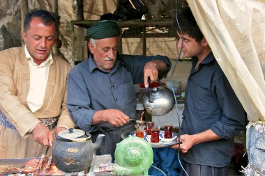 Tea serving and kebab roasting in small shack by road. Iraq. Middle East. clipart