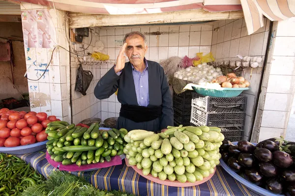 Μπακάλη χαιρετά τον πελάτη που στέκεται πίσω από τα λαχανικά σε μικρό κατάστημα στο παζάρι. Halabja, Ιράκ, Μέση Ανατολή. — Φωτογραφία Αρχείου