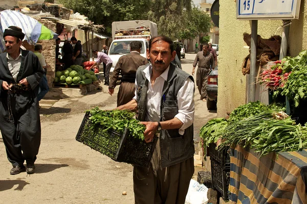 Grocer carrying vegetables to his stand on bazaar (market) in Iraq — Stock Photo, Image