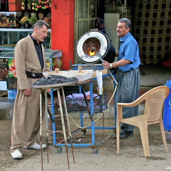 Man waiting for his serving of flame roasting nuts. Iraq. — Stock Photo, Image