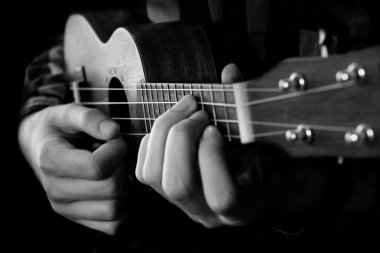 Ukulele gitar çalarak erkek elini kapat. Siyah ve beyaz yakın çekim fotoğrafçılık.