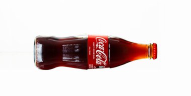 Chisinau, Moldova - July 31, 2022: Glass bottle of Coca Cola drink on white background. The drink is produced and manufactured by The Coca-Cola Company.