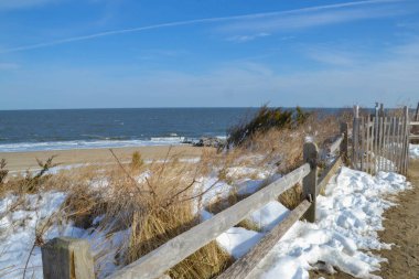 Lewes, Delaware 'deki Cape Henlopen Eyalet Parkı plajındaki kum tepelerini kar kaplıyor.