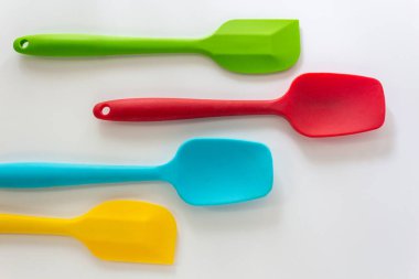 Silikon spatulası çeşitli renklerde, kırmızı, mavi, yeşil ve sarı beyaz arkaplanda yatar