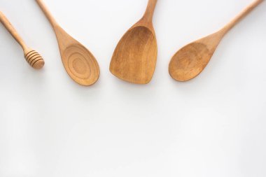 Ahşap mutfak aletleri, kaşık, bal kaplama ve spatula, beyaz arka planda üst görüntü..