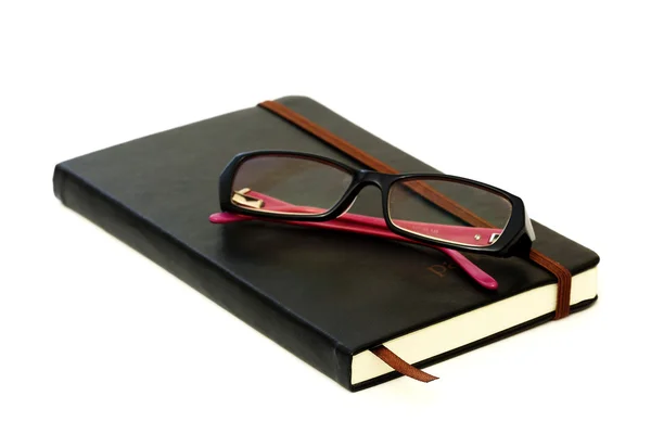 Fechado livro de laticínios e óculos — Fotografia de Stock