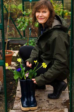 Çekici ve güler yüzlü esmer bir kadının bir çizme çiftliğine bahar ampulleri yerleştirmesi..