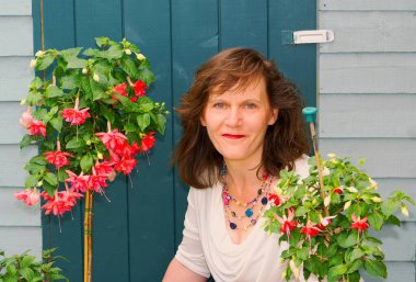 Çekici, esmer bir kadının Haziran 2022 'de çiçek açan standart fuşyalar sergilemesi..