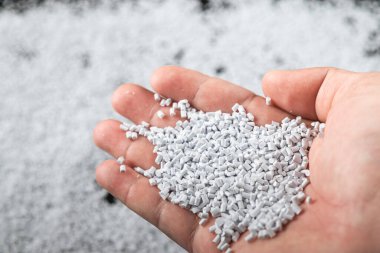 Ahşap arka planda beyaz plastik boncuklar polimer reçine, polimer palet petrokimyasal fabrikalardan alınmış ürünler. granüller polimer,