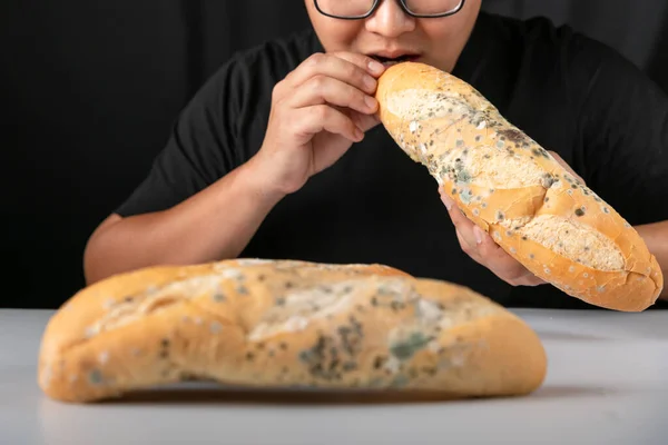 Man eating moldy dirty bread. man standing holding moldy bread. Moldy bread on blurry background. food fungus. Dirty food that is unappetizing.