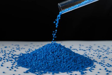 Ahşap arka planda mavi plastik boncuklar, polimer reçine, polimer palet, petrokimyasal fabrikalardan alınmış ürünler. Granüller polimer, evin çatısının polimer plastikten yapıldığını varsayın..