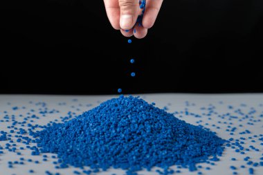 Ahşap arka planda mavi plastik boncuklar, polimer reçine, polimer palet, petrokimyasal fabrikalardan alınmış ürünler. Granüller polimer, evin çatısının polimer plastikten yapıldığını varsayın..
