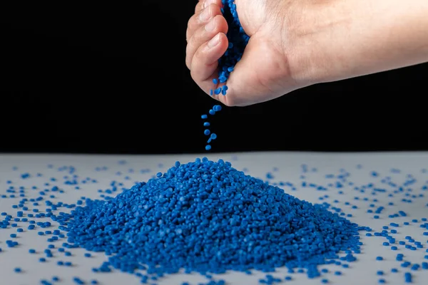 Ahşap arka planda mavi plastik boncuklar, polimer reçine, polimer palet, petrokimyasal fabrikalardan alınmış ürünler. Granüller polimer, evin çatısının polimer plastikten yapıldığını varsayın..