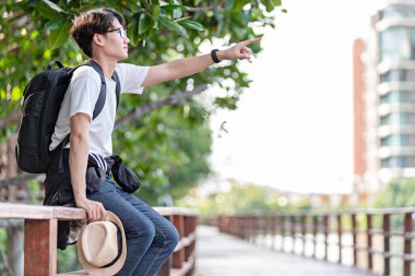 Mutlu adam mangrov ormanlarında seyahat eder. Turist gezginler sırt çantası aktivitesi için şapkalı beyaz gömlek giyerler. Asyalı adam yürüyüşe çıkmaya hazır. Tatil konsepti seyahatinde dinlenme zamanı.