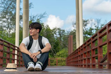 Mutlu adam mangrov ormanlarında seyahat eder. Turist gezginler sırt çantası aktivitesi için şapkalı beyaz gömlek giyerler. Asyalı adam yürüyüşe çıkmaya hazır. Tatil konsepti seyahatinde dinlenme zamanı.