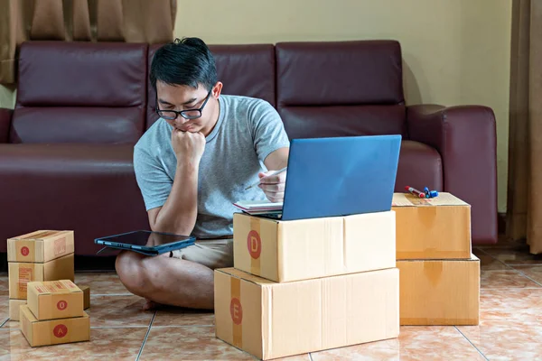 Man wearing grey shirt will send the parcel. box delivery concept. Packaging boxes for express delivery. happy man  with pick up and delivery with fast delivery service. transportation concept. man using notebook and tablet to search for customer inf