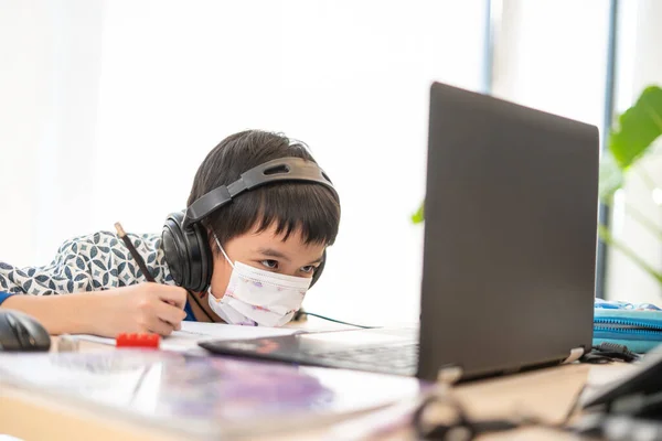 Asyalı çocuk evde karantina salgını sırasında dizüstü bilgisayar kullanmaktan mutlu, sohbet arkadaşı, öğretmen ya da bilgisayar yoluyla ebeveyn. evde eğitim, çevrimiçi öğrenim, çevrimiçi öğrenim, korona virüsü veya teknoloji konsepti