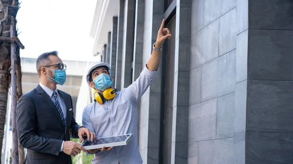 Yeni normalde çalışan proje mühendisi ve takım lideri maske takıyor. Binanın güneş pili sisteminde danışmanlık. Mühendisler güneş enerjisinin temiz enerji üretimi için kullanımını tartışıyor.